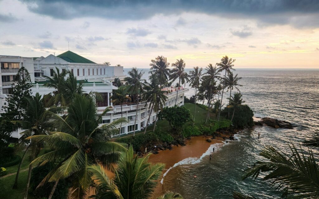 Beautiful ocean view with palm trees and a resort.