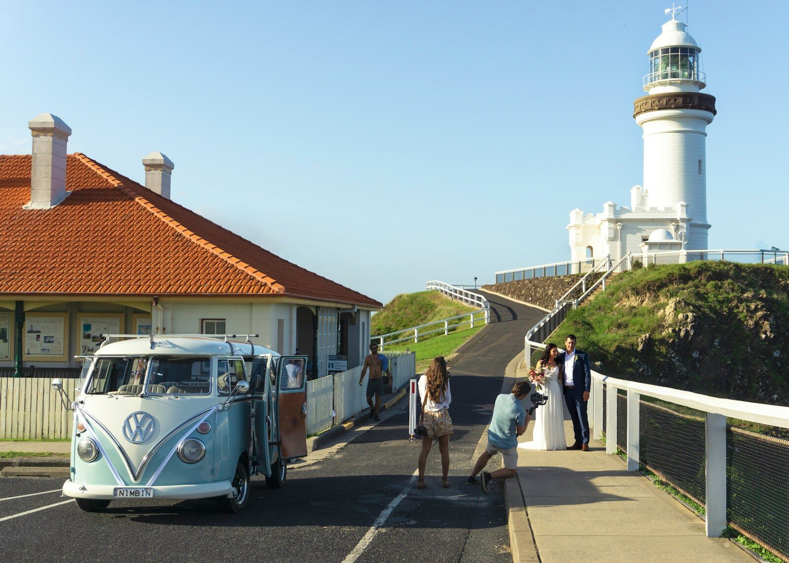 a white vw bus parked next to a white lighthouse