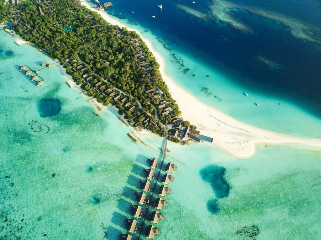 aerial shot of nipa huts on body of water near island